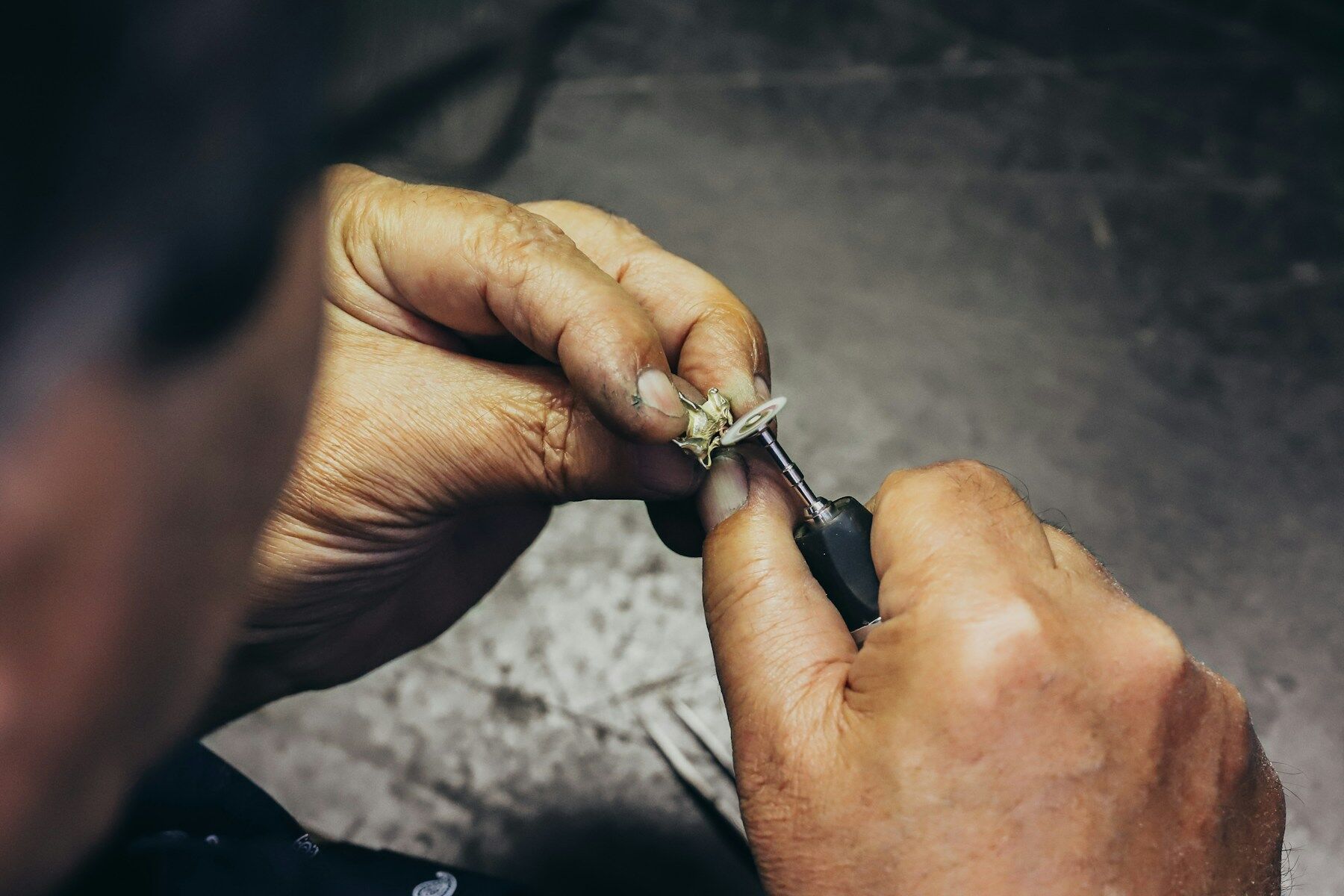 Mains d'un joaillier sertissant une bague à l'établi